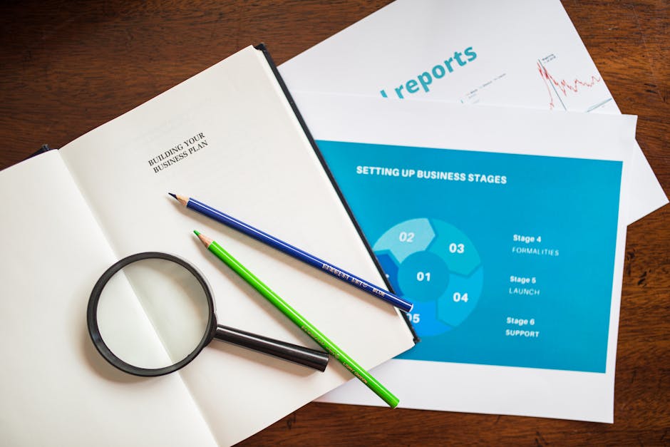 Flat lay of business plans, reports, and magnifying glass, ideal for business analysis concepts.